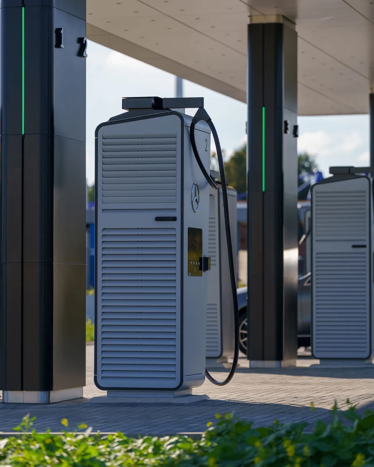 An outdoor electric-vehicle charging station with several charging units lined up beneath a shade canopy.